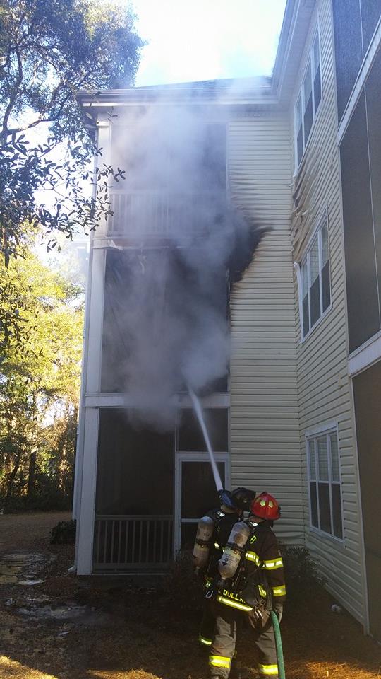 Firefighters Spraying a Hose on the Second Floor of a Smokey Building