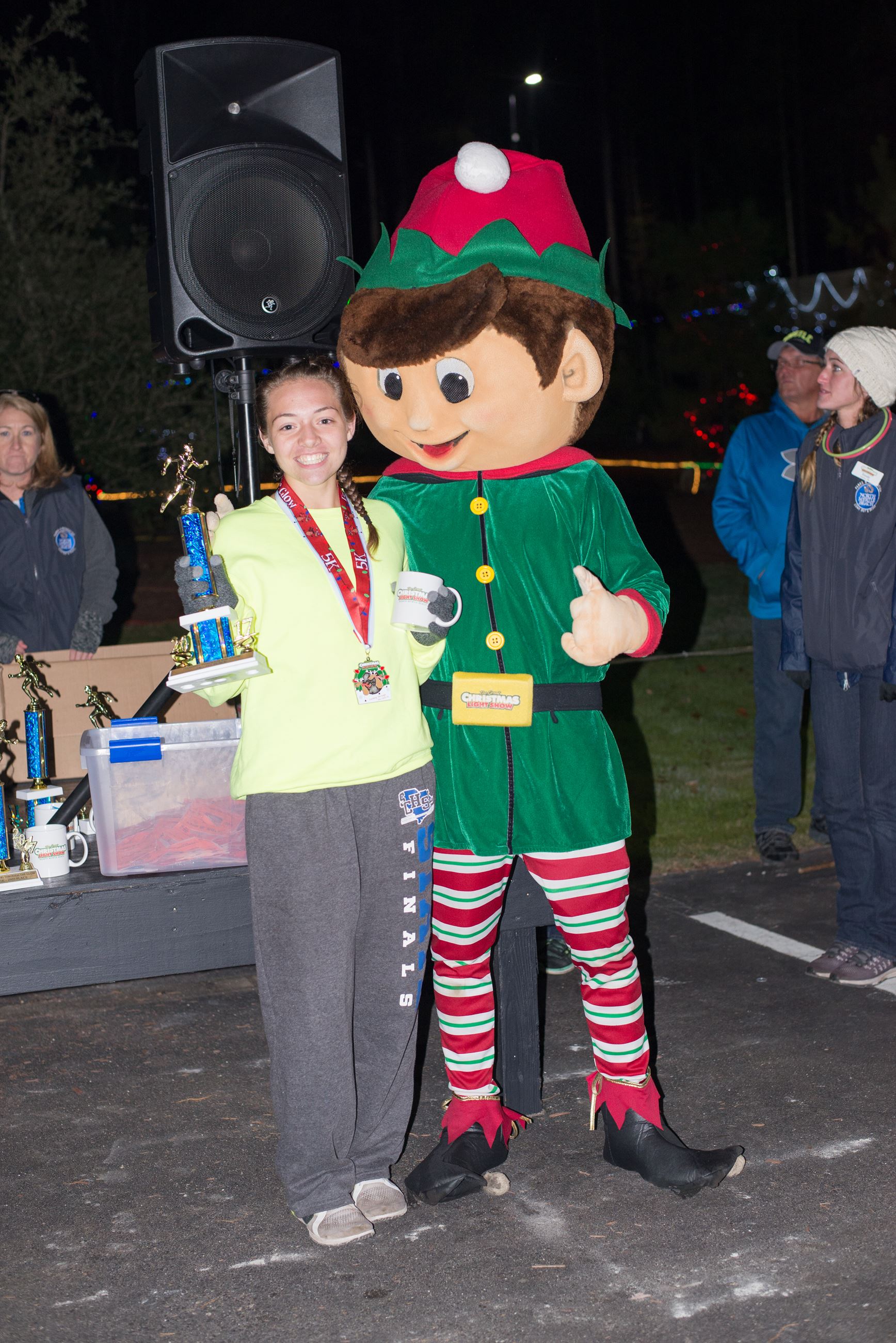 Young Woman Holding a Mug and Trophy Posing with an Elf